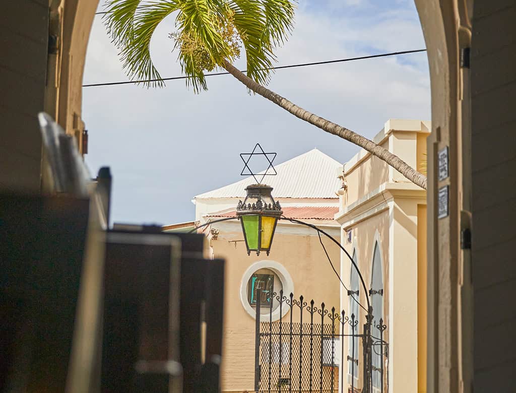 A synagogue is visible beyond a gate with a lantern in USVI.