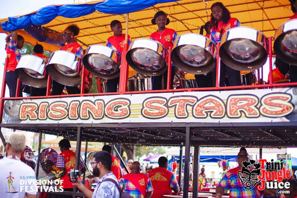 A group of musicians play steel drums on a double-decker float decorated with 