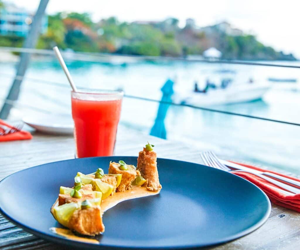A plate of food on a table with water in the background at Sunset Grille at Secret Harbour in St Thomas, USVI