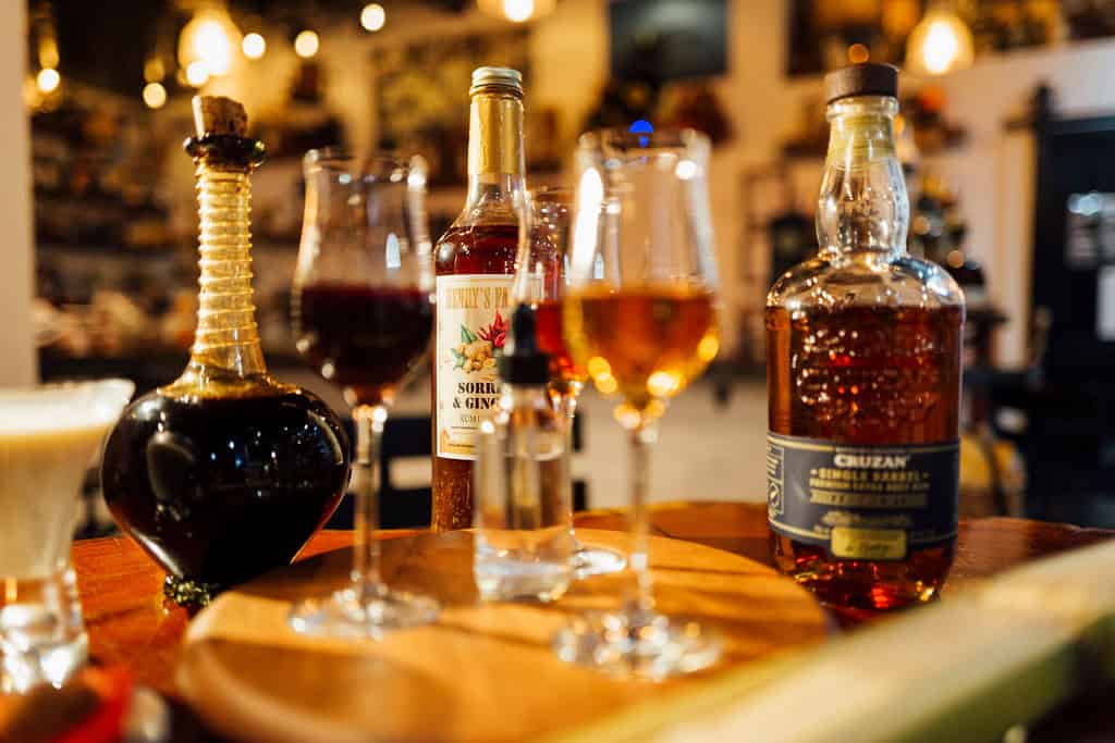 A selection of liquor bottles and glassware on a wooden surface in a warmly lit bar setting in the U.S. Virgin Islands.