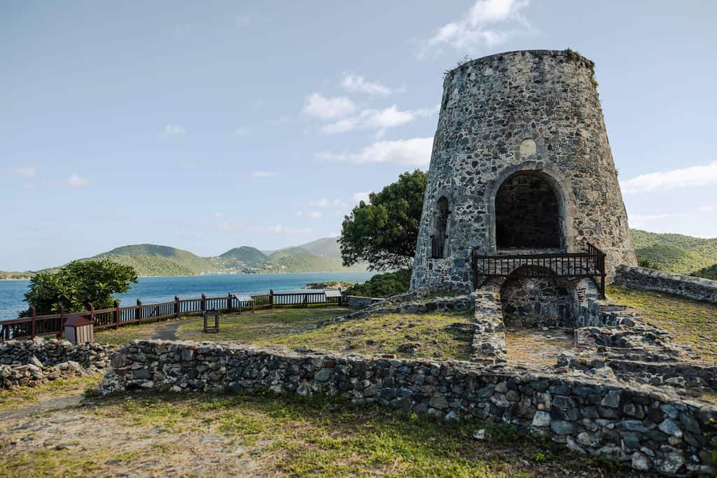 Ruins of Annaberg Sugar Plantation on a grassy hill with a view of the bay and mountains in the background in St. John, USVI.