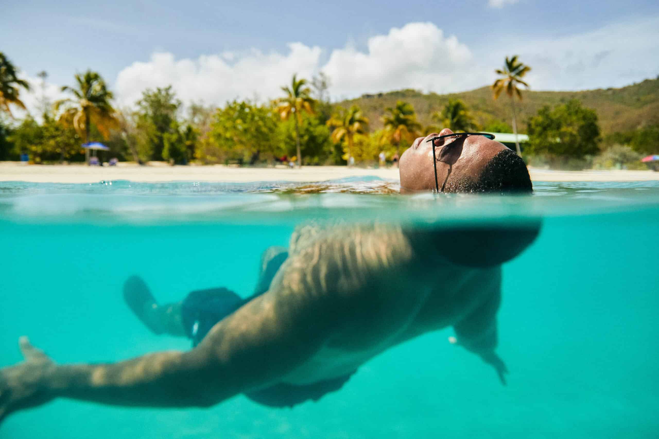 Man floats on his back in turquoise water at Magens Bay Beach on St. Thomas in the USVI.