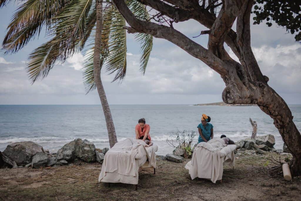 Two people getting massages along the shore of the Tamarind Reef Resort Spa & Marina