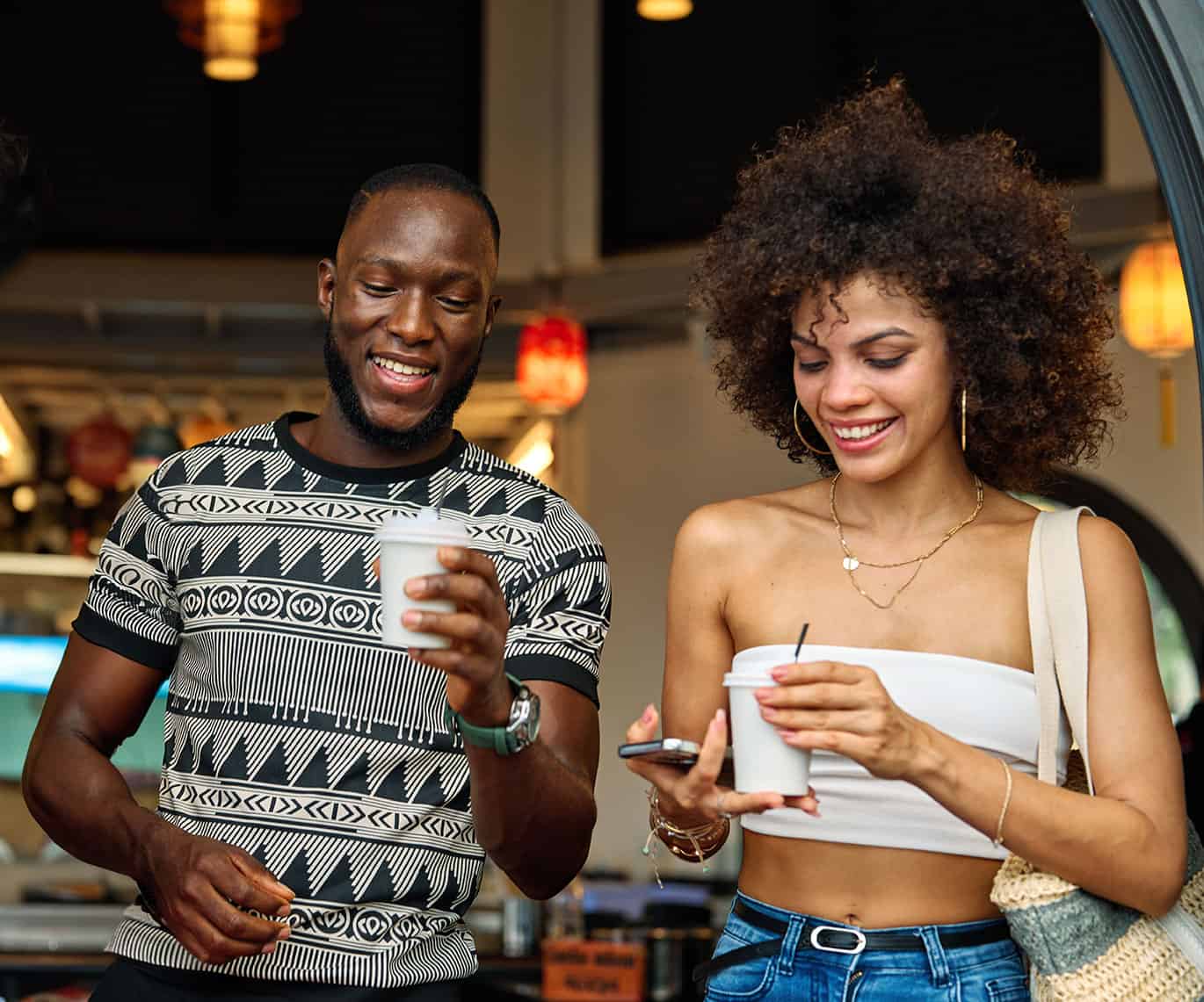 A man and a woman hold disposable cups of coffee. AdobeStock_1633711800