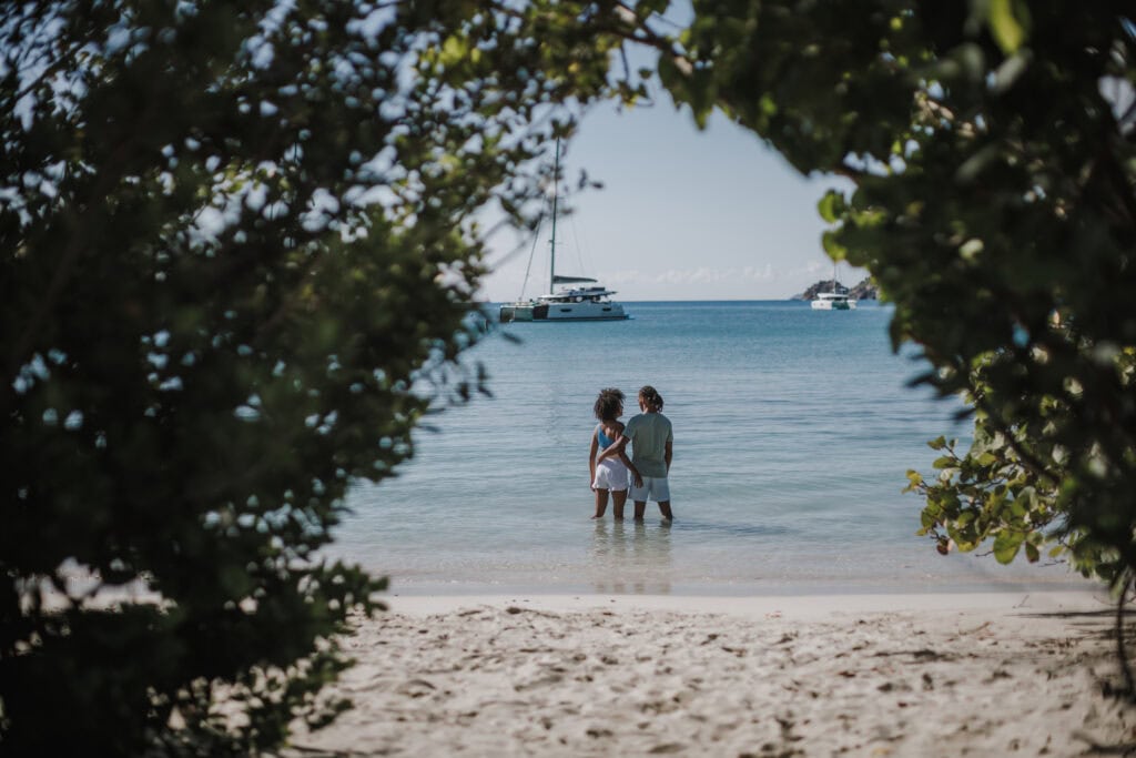 A couple stands in shallow water just off the shore of Maho Beach on St. John, USVI