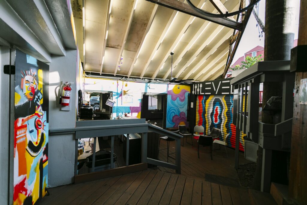 Outdoor art space with colorful murals on walls, wooden flooring, chairs, and a partially covered ceiling with string lights at Levels nightclub in Christiansted on St. Croix, USVI.