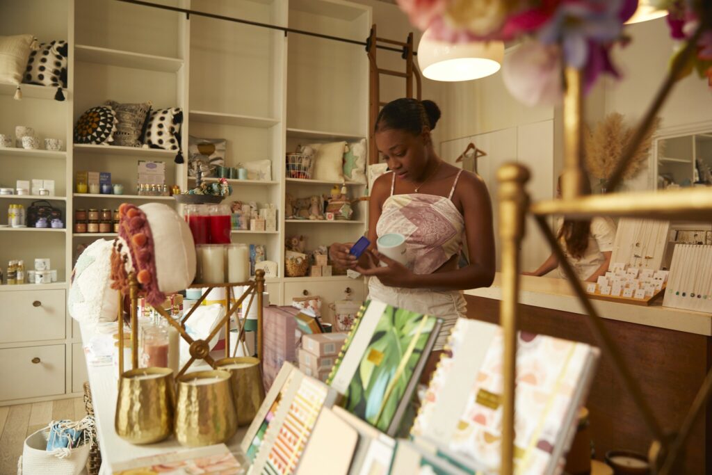 A woman stands in a boutique store in Christiansted on St. Croix in the USVI, examining a product. Shelves and displays around her hold candles, stationery, and various decorative items.