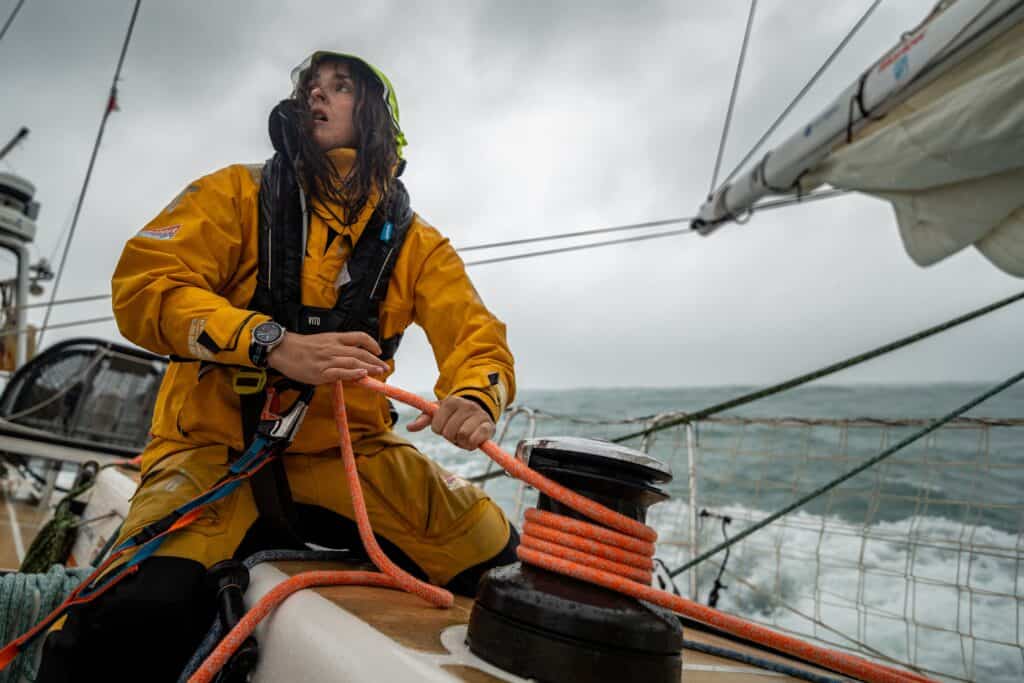 Person in yellow rain gear operates a winch on Clipper Race sailing yacht during rough weather, with waves and cloudy skies in the background. Crews sail vessels in the Clipper Round the World Yacht Race. The U.S. Virgin Islands will serve as a host port and Team Partner in the 2027-28 race. PHOTO REQUIRES A CLIPPER RACE CREDIT.