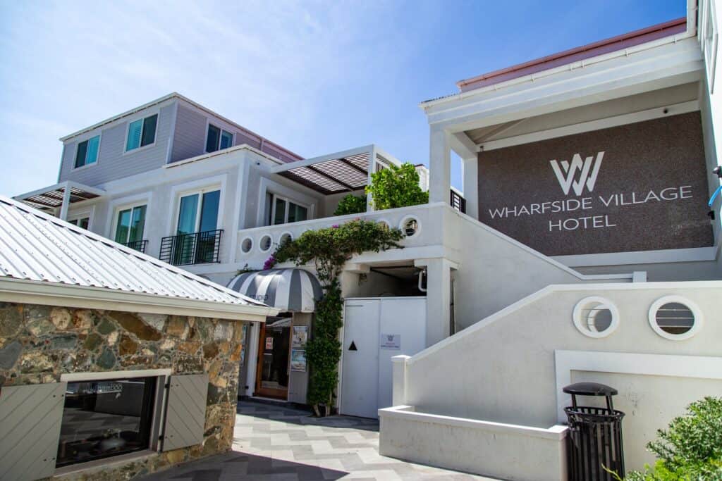 Exterior of the Wharfside Village Hotel featuring white buildings, stone walls and a staircase on St. John, USVI.