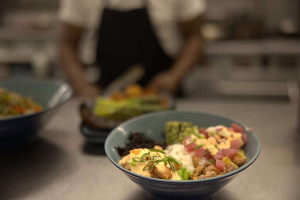 A poke bowl featuring raw tuna, edamame and sauce in a blue bowl on a kitchen counter at Tarpon's Table on St. Thomas, USVI.